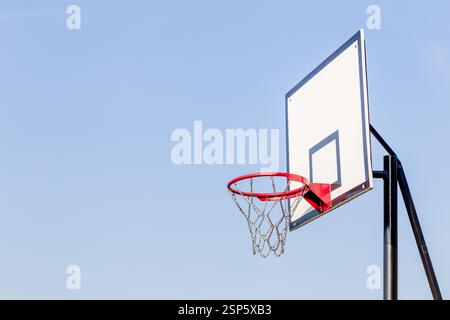 Ein Basketball-Rückbrett und ein Basketball-Basketball-Korb, der vor einem klaren blauen Himmel steht. Stockfoto