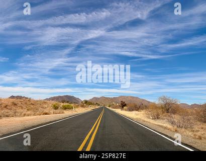 Wüstenautobahn führt zu entfernten Arizona-Bergen unter blauem Himmel Stockfoto
