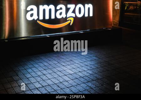 Beleuchtetes neonfarbenes Schild mit dem Amazon-Firmenlogo im Logistikzentrum. Bürogebäude i des amerikanischen multinationalen Technologieunternehmens Amazon.com, Inc Stockfoto