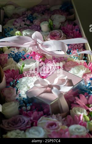 Geschenkbox mit Blumen und Parfüm, verpackt in ein rosafarbenes Band Stockfoto