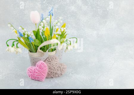 Frühjahrsangebot-Konzept. Einkaufstasche mit traditionellen Blumen und handgefertigten Herzen. Grußkarte, Überraschung oder Geschenkkonzept. Pastelldesign, heller Hintergrund Stockfoto