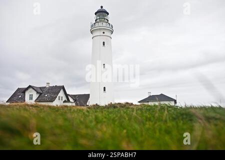 Weißer Leuchtturm mit schwarzer Kuppel, hoch vor einem bewölkten Himmel. Stockfoto