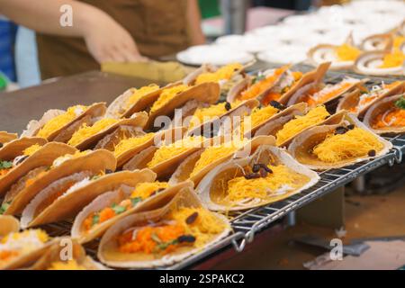 Nahaufnahme von knusprigen thailändischen Pfannkuchen, bekannt als Khanom Bueang, garniert mit Kokoscreme, goldenen Eierfäden (Foi Thong) und anderen süßen Füllungen. Stockfoto