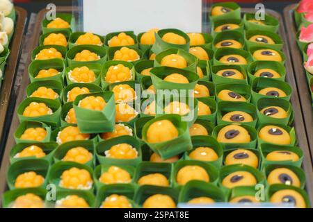 Nahaufnahme traditioneller thailändischer goldener Süßigkeiten aus Eigelb und Zucker, elegant präsentiert in kleinen Bananenblattbechern. Diese bissgroßen Konfekt Stockfoto