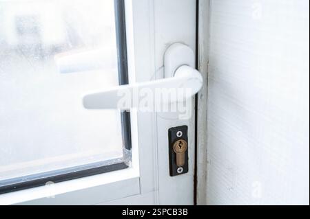 Türgriff aus weißem Kunststoff, Nahaufnahme. Die Tür hat ein Fenster. Eine Nahaufnahme einer Tür Stockfoto