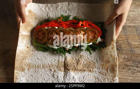 Schawarma in Lavash mit Huhn und Gemüse einwickeln. Stockfoto