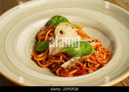 Eine wunderschön überzogene Portion Spaghetti mit reichhaltiger Tomatensauce, garniert mit frischen Basilikumblättern und geriebenem Parmesankäse. Das Gericht ist ser Stockfoto