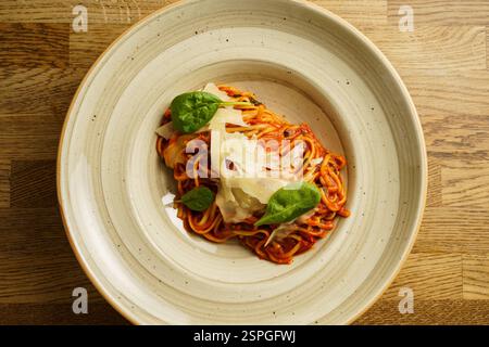 Eine wunderschön überzogene Portion Spaghetti mit reichhaltiger Tomatensauce, garniert mit frischen Basilikumblättern und geriebenem Parmesankäse. Das Gericht ist ser Stockfoto