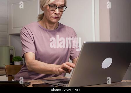 Eine ältere Frau beschäftigt sich mit Online-Buchhaltung Stockfoto