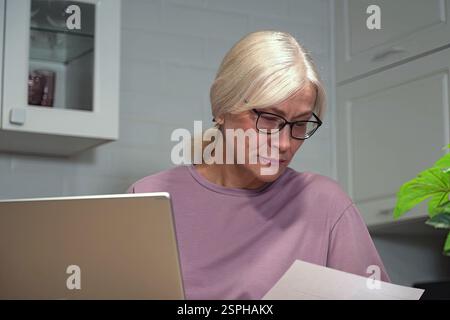 Frau, die Dokumente zu Hause überprüft Stockfoto