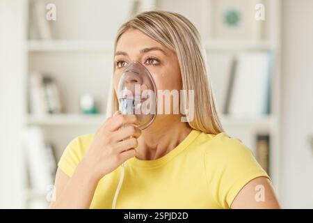 Junge Frau, die zu Hause einen Inhalator benutzt Stockfoto