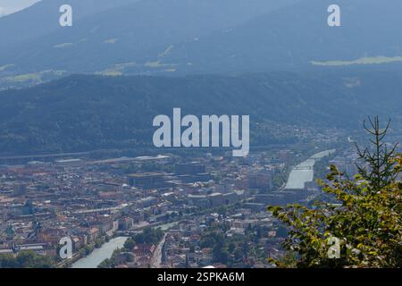 Weitwinkelaufnahme von Innsbruck, Österreich. Ein Fluss schlängelt sich durch die Stadt, die in einem Tal eingebettet ist, das von Bergen umgeben ist. Die Abbildung zeigt d Stockfoto