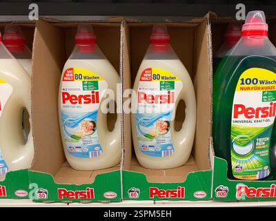 Drei große Persil-Waschmittelflaschen befinden sich in einem Verkaufsregal. Zwei sind cremefarben und mit „Sensitive Gel“ beschriftet, während einer grün und Lab ist Stockfoto