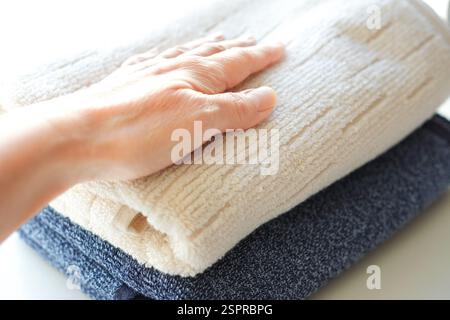 Frau, die flauschiges Handtuch auf weißem Hintergrund berührt Stockfoto