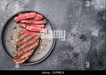 Gegrilltes New Yorker Striploin-Steak, perfekt angebraten mit schönen Grillmarkierungen, die seine saftige Zartheit und seinen reichen Geschmack zeigen. Schwarzer Hintergrund. Oben Stockfoto