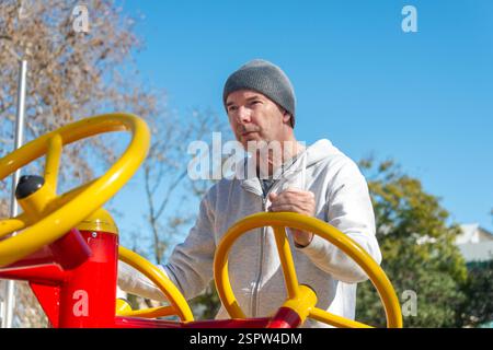 Mann, der ein Fitnessstudio im Freien benutzt, mit drehendem Rad, Tai Chi-Übung. Stockfoto