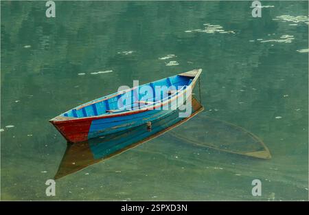 Pokhara, Nepal - 7. Februar 2025 - Ruderboot schwimmt auf einem See über einem versunkenen Boot Stockfoto
