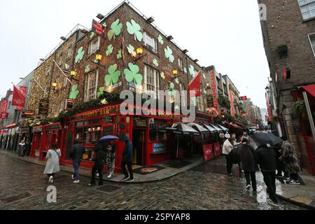 Dublin, Irland - 14. Februar 2025 - der Temple Bar Pub ist mit grünen Schamfelsen dekoriert, während die Menschen an einem nassen Tag mit starkem Regen in Dublin vorbeikommen Stockfoto