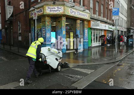 Dublin, Irland - 14. Februar 2025 - ein Mitarbeiter des Stadtrates von Dublin schiebt an einem nassen Tag in Dublin eine Straßenkehrmaschine auf den Fußweg des Aston Quay Stockfoto