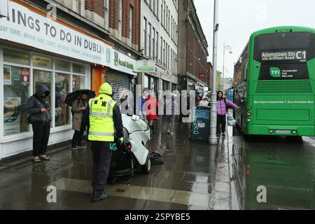 Dublin, Irland - 14. Februar 2025 - ein Mitarbeiter des Stadtrates von Dublin schiebt an einem nassen Tag in Dublin eine Straßenkehrmaschine auf den Fußweg des Aston Quay Stockfoto