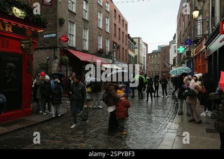 Dublin, Irland - 14. Februar 2025 - Touristen halten an einem nassen Tag in Dublin, um Fotos vor dem Temple Bar Pub in Temple Bar zu machen Stockfoto
