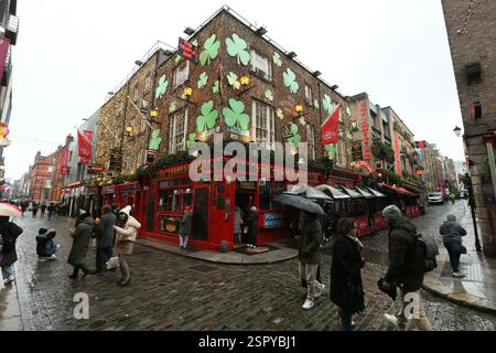 Dublin, Irland - 14. Februar 2025 - Touristen halten an einem nassen Tag in Dublin, um Fotos vor dem Temple Bar Pub in Temple Bar zu machen Stockfoto