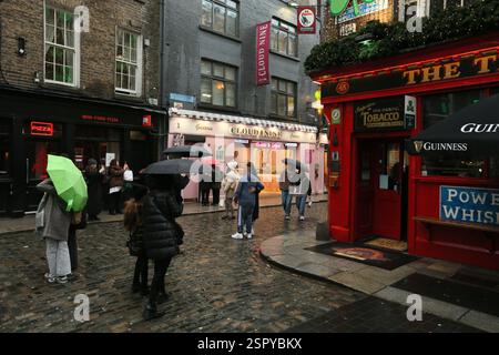 Dublin, Irland - 14. Februar 2025 - Touristen halten an einem nassen Tag in Dublin, um Fotos vor dem Temple Bar Pub in Temple Bar zu machen Stockfoto
