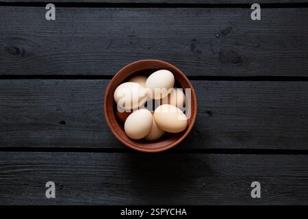 Braune Hühnereier in einer Tonschale auf einem Holztisch, Eier Stockfoto