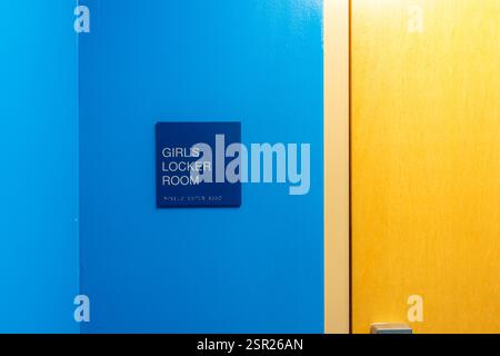 Blaues Schild in der Umkleidekabine für Mädchen an der blauen Außenwand neben einer geschlossenen Holztür. Stockfoto