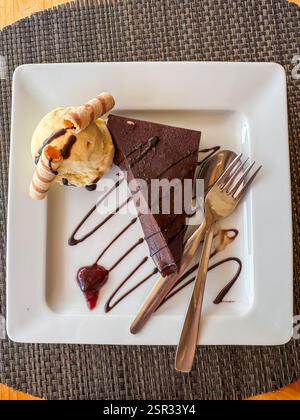 Reichhaltiger Schokoladenkuchen mit Vanilleeis und dekorativen Waffelbrötchen. Stockfoto