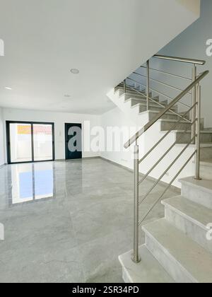 Moderner, offener Wohnbereich mit Edelstahltreppe und reflektierendem Fliesenboden. Stockfoto
