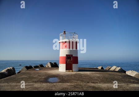 Nazare, Portugal - 27.12.2022: Ein bezaubernder Leuchtturm hoch am Ozean an einem hellen und klaren Tag des blauen Himmels Stockfoto