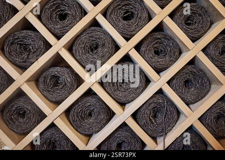 Kugeln aus dunklem Garn liegen im Holzschrank Stockfoto