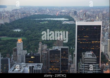 Die Skyline von Manhattan in New York City explodiert bei Nacht mit einem pulsierenden Licht. Die Gebäude am Ufer schimmern in verschiedenen Farben und spiegeln sich auf Th Stockfoto