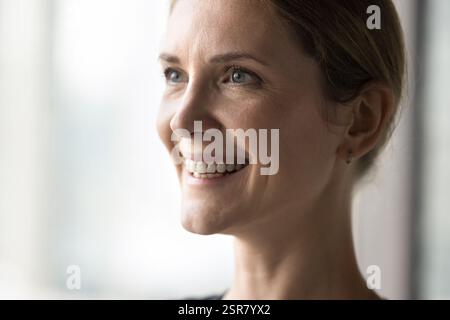 Nahaufnahme lächelnde Frau mit positivem Ausdruck, die in die Distanz schaut Stockfoto