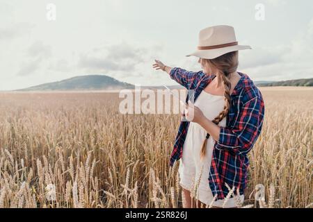 Eine junge Frau auf einem Weizenfeld, die eine Tafel hält Stockfoto