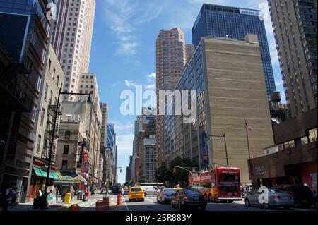 Wolkenkratzer durchdringen den Himmel in New York, Manhattan. Taxis schlängeln sich durch den geschäftigen Rushhour-Verkehr, einen Betondschungel voller urbaner Energie. Stockfoto