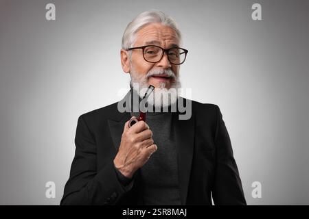 Seniorenmann mit Tabakpfeife auf hellgrauem Hintergrund Stockfoto