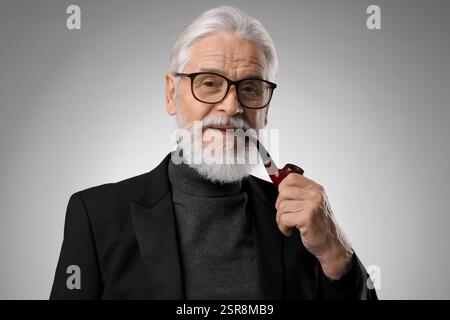 Seniorenmann mit Tabakpfeife auf hellgrauem Hintergrund Stockfoto