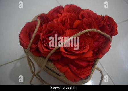 Eine schöne Nahaufnahme von frisch gepflückten roten Rosen, elegant in einer rustikalen Jutebox angeordnet. Dieses fesselnde Bild fängt die natürliche Schönheit des R ein Stockfoto