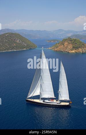 Luftaufnahme der Segelyacht Nirvana im ruhigen Blauen Meer in der Nähe einer grünen Insel unter klarem Himmel in Turkiye. Stockfoto