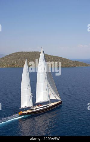Luftaufnahme der Segelyacht Nirvana im ruhigen Blauen Meer in der Nähe einer grünen Insel unter klarem Himmel in Turkiye. Stockfoto