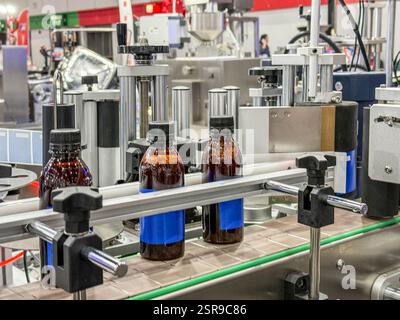 Glasflaschen in einem Förderband auf einer hochwertigen automatischen vertikalen Abfüllmaschine. In der Produktionslinie des Werks Stockfoto