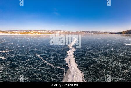 Blick von oben auf den Blue Clear Ice Lake Baikal. Rissüberzug auf gefrorenem Wasser. Kalte Winterlandschaft mit Bergen, sonniger Tag, Natur Stockfoto