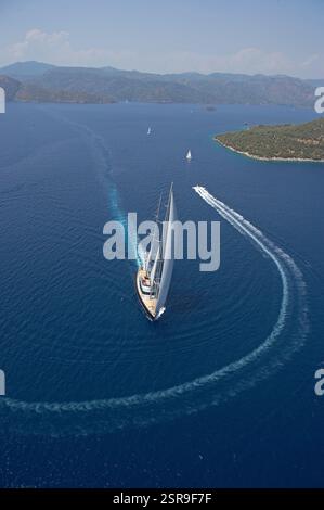 Luftaufnahme der Segelyacht Nirvana im ruhigen Blauen Meer in der Nähe einer grünen Insel unter klarem Himmel in Turkiye. Stockfoto