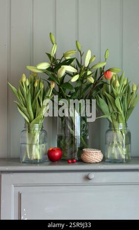 Tulpenstrauß in einer Glasvase auf einem Olivenschrank. Frühlingsblumen Nahaufnahme Foto. Muttertagsfeier-Konzept. Stockfoto