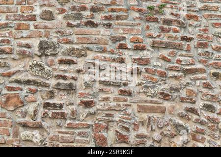 Rustikale toskanische Mauer mit freiliegenden Ziegeln und Steinen, die traditionelle Handwerkskunst zeigen. Perfekt für Architekten, historische und Textur-Design-Profis Stockfoto