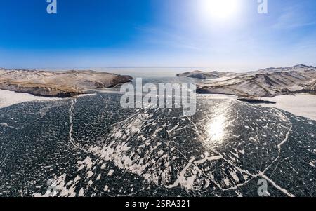 Blick von oben auf den Blue Clear Ice Lake Baikal. Rissüberzug auf gefrorenem Wasser. Kalte Winterlandschaft mit Bergen, sonniger Tag, Natur Stockfoto