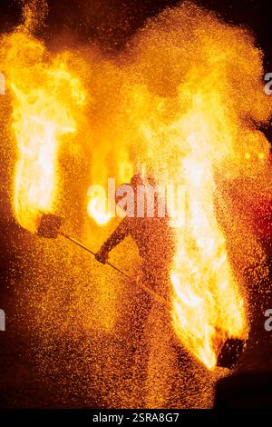 Silhouette zweier Feuerkünstler mit funkelndem Feuerwehrpersonal, das am Nachthimmel ausbricht und die Energie und Kunst der Feuermanipulation während eines Outdours zeigt Stockfoto