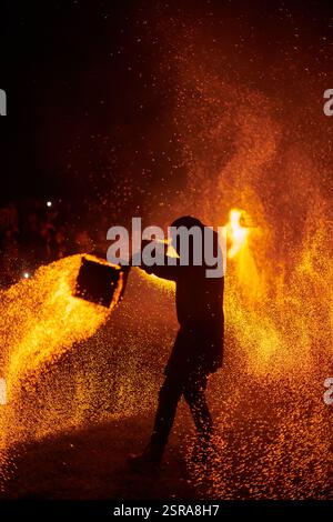 Silhouette zweier Feuerkünstler mit funkelndem Feuerwehrpersonal, das am Nachthimmel ausbricht und die Energie und Kunst der Feuermanipulation während eines Outdours zeigt Stockfoto